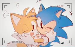 Size: 2000x1266 | Tagged: safe, artist:c52278, miles "tails" prower, sonic the hedgehog, 2021, blushing, classic sonic, classic tails, cute, duo, gay, grey background, hugging, looking at camera, one eye closed, recording, shipping, simple background, smile, sonabetes, sonic x tails, standing, tailabetes
